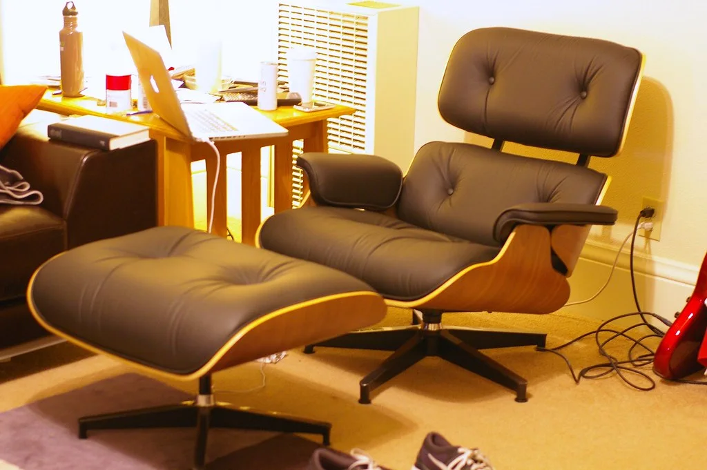 Eames Lounge Chair: A low chair and ottoman with curved plywood shells, padded leather cushions, and a swivelling base.